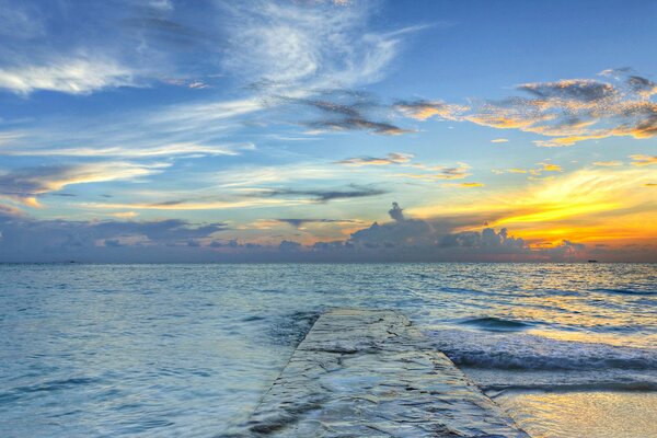 Sea sunset on the pier. Clouds in the sky