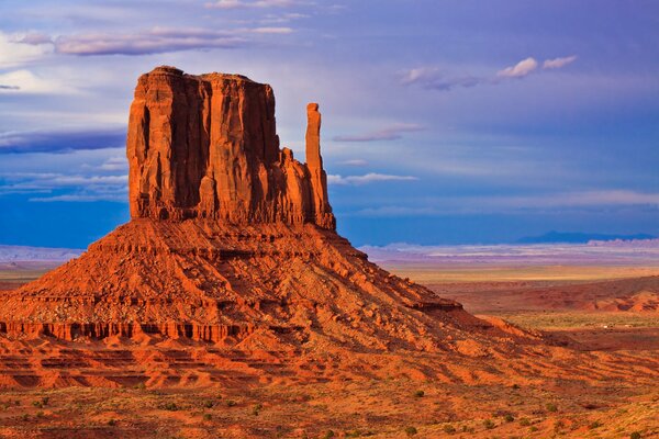 Orange sandy rocks against a blue cloudy sky