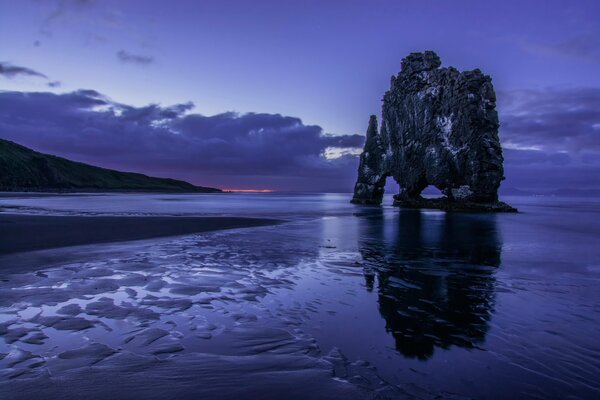 Bloc gris de roches sur le rivage, sur fond de ciel lilas