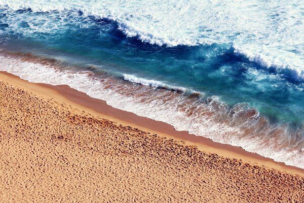 Warmer Sand mit Meeresschaum bedeckt