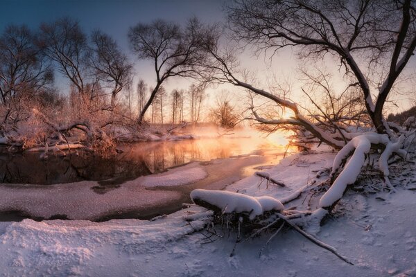 Sonnenuntergang und gefrorener Fluss im Schnee