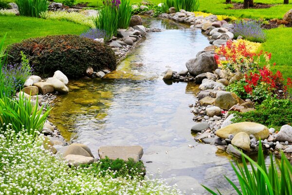 A stream flows through a lawn with flowers