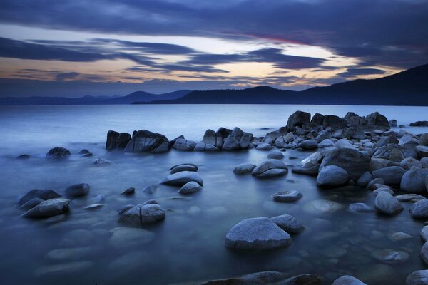 Stones on the seashore against the background of mountains and clouds