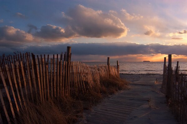 Route de la plage entre les clôtures au coucher du soleil