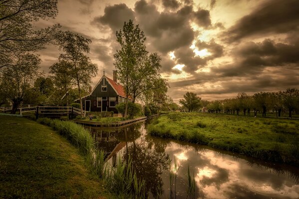 Maison avec lac et verdure sous les nuages crépusculaires