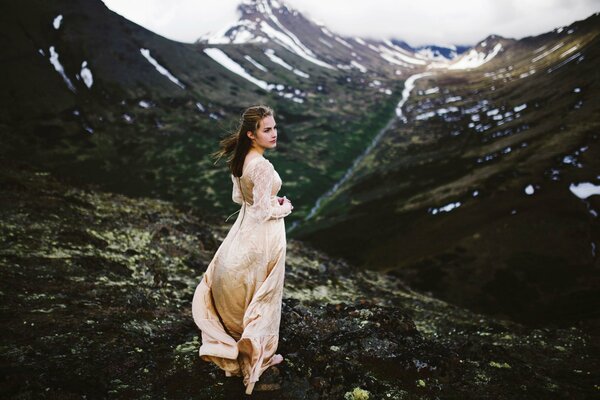 A girl in a white dress on the background of mountains