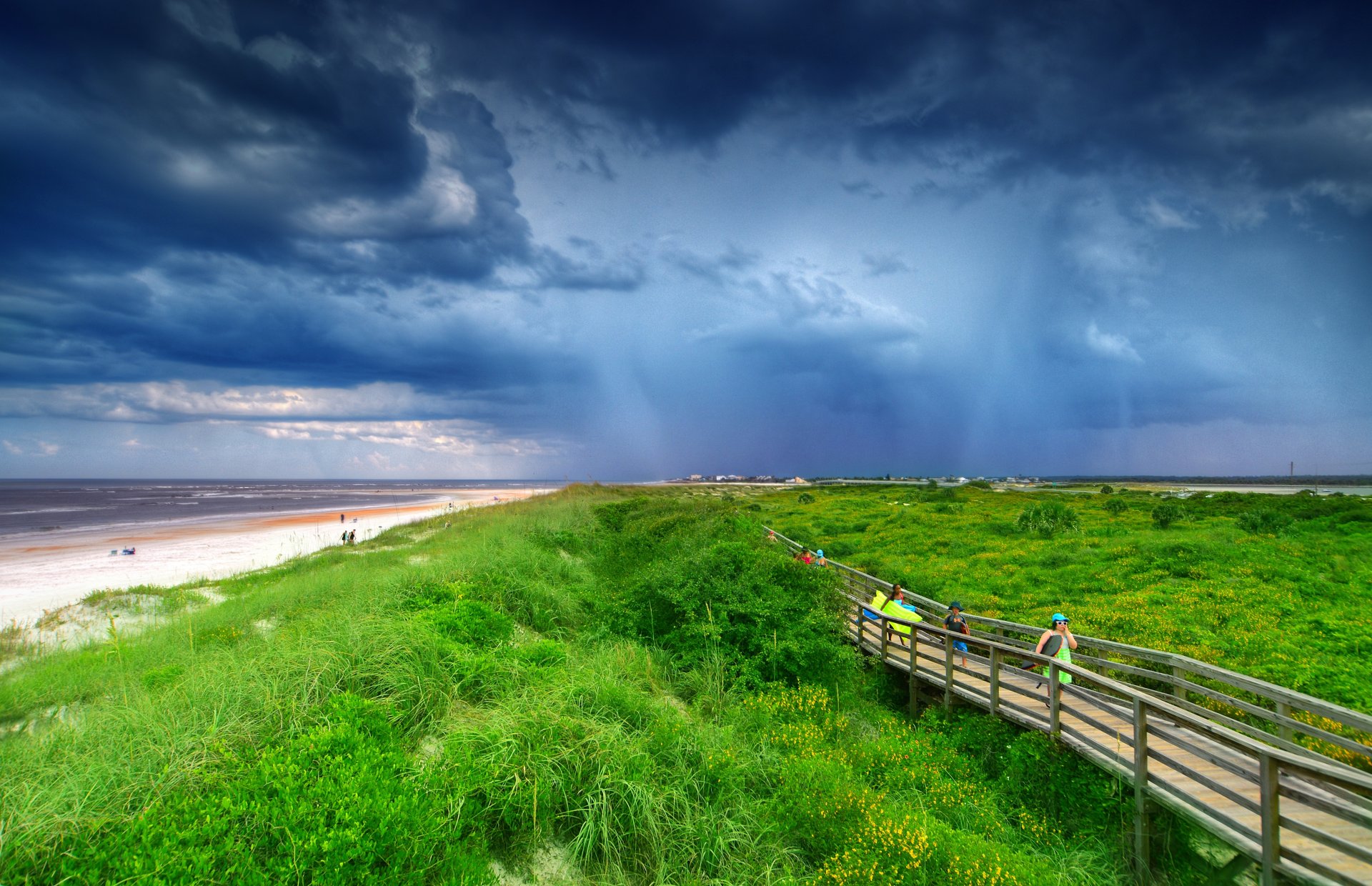 plaża morze piasek trawa most ludzie chmury