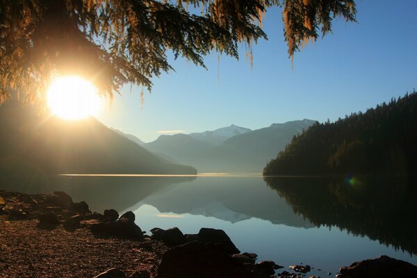 Die Strahlen der Morgensonne über einem klaren See in den Bergen