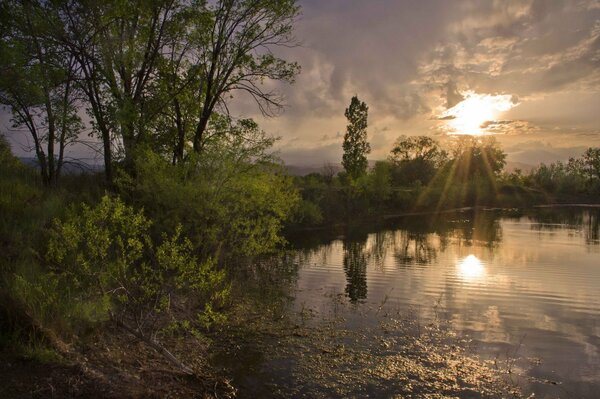 A calm lake with the rays of the sun