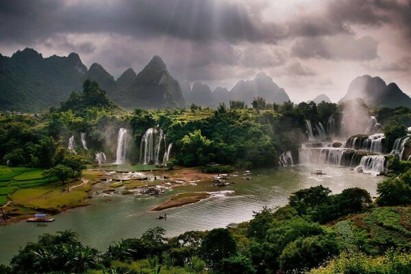 Paisaje con un cuerpo de agua y cascadas bajo los rayos del sol a través de las nubes