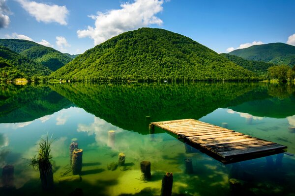 Posto verde con molo, montagne, fiume