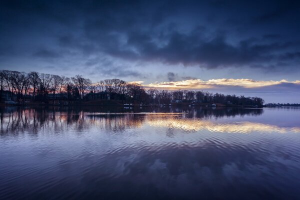 Die Reflexion der blauen Wolken und Bäume im Fluss