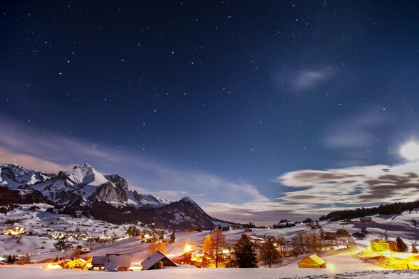 Lights in houses and foothills of mountains under the starry sky in winter