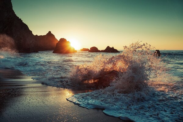 Éclaboussures de vagues sur la plage au coucher du soleil