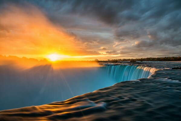 Niagara Falls against the background of the extraordinary beauty of the sunrise blinding the human eye