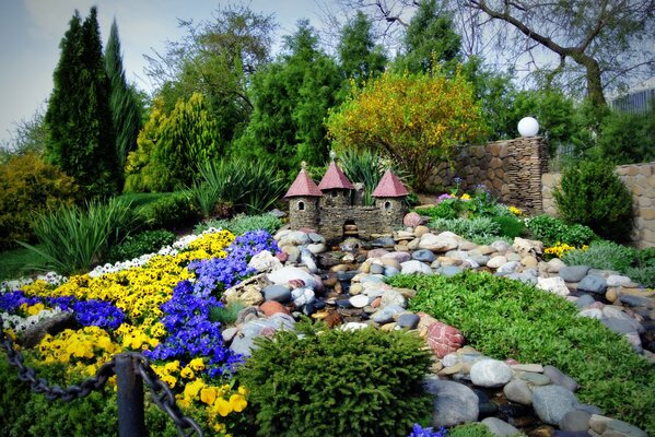 A small castle in the middle of stones and flowers