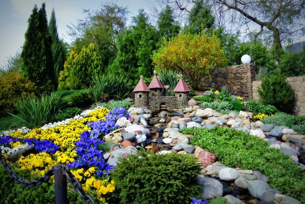 Mały zamek pośrodku kamieni i kwiatów