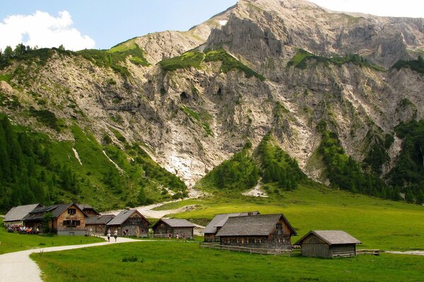 Eine Berglandschaft mit kleinen Holzhäusern mit viel Grün und einem teuren sonnigen Sommertag