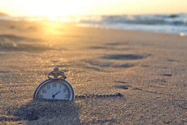 Soleil brillant sur le rivage. Horloge dans le sable