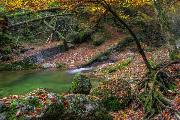 Lake with a small waterfall in the mountains in autumn