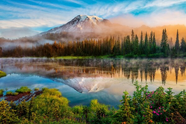 Morgennebel über einem See umgeben von Bergen