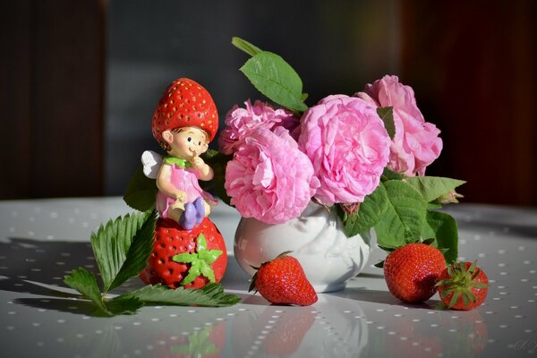 Flores Rosadas en un jarrón blanco junto a las bayas de fresa