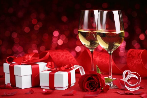 Champagne glasses with a red rose and gifts