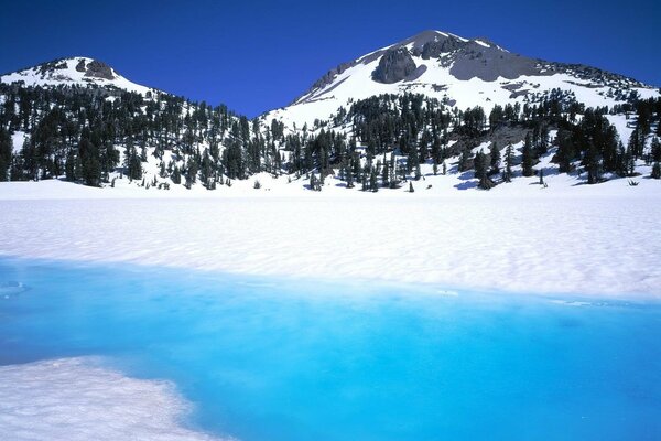 White snow, blue river on the background of mountains