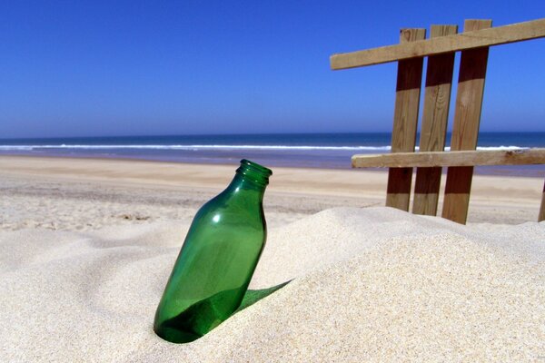 An empty bottle stuck in the sand on the seashore