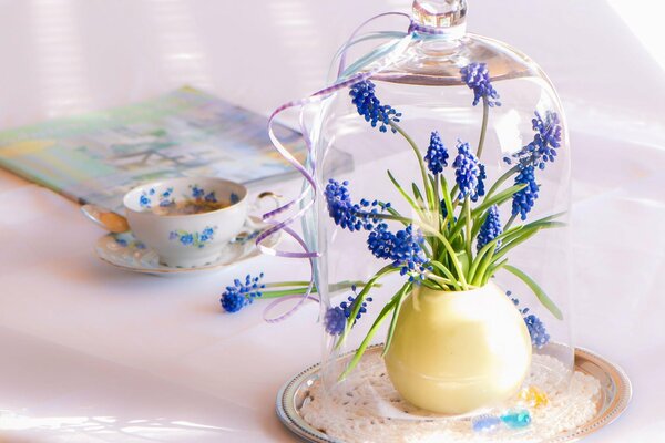 Tasse de thé et bouquet de fleurs dans un flacon en verre