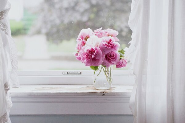 Fleurs roses dans un vase sur la fenêtre