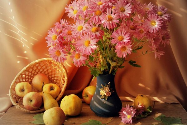 Blumen stehen in einer Vase und neben einem Korb mit Äpfeln