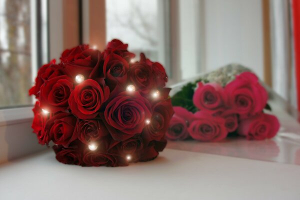 A bouquet of scarlet roses and a bouquet of red roses are lying on the windowsill