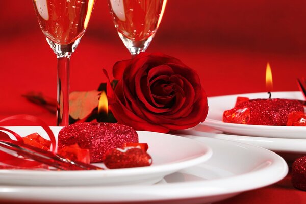 Candlelit dinner . Glasses and a red rose