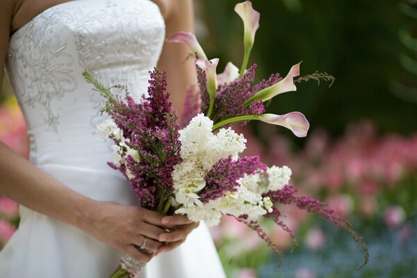 Die Braut hält einen Blumenstrauß in ihren Händen
