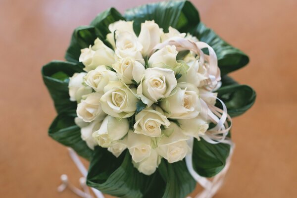 Delicate wedding bouquet with roses on a beige background