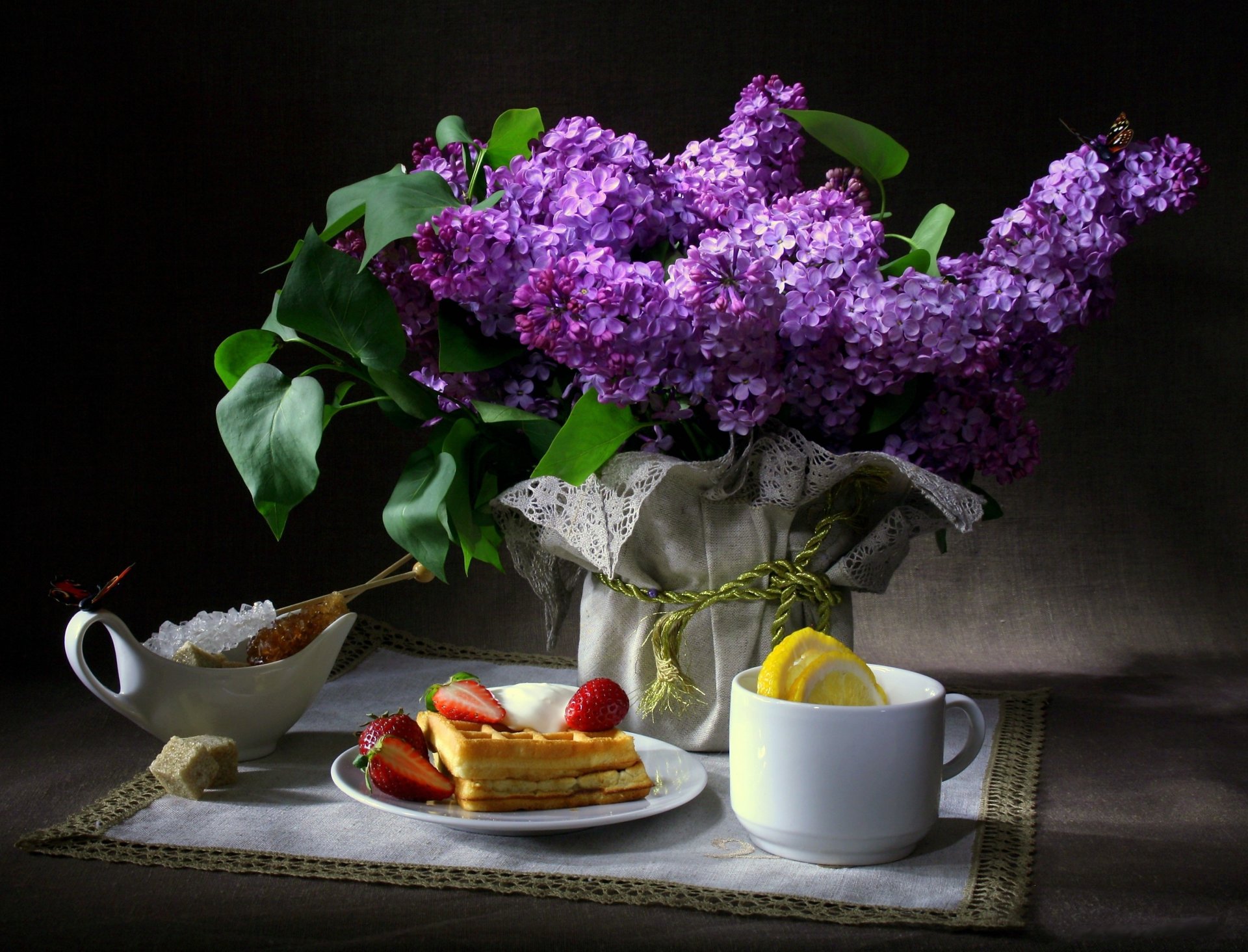 stillleben blumen flieder schmetterlinge frühstück waffeln erdbeere tasse zitrone zucker serviette dunkler hintergrund