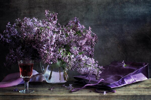 Bouquet of lilacs in a vase with a glass of wine