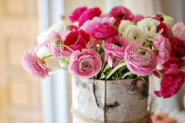 The most delicate bright pink bouquet of amazing beauty of flowers in a birch bark basket on a light brown background