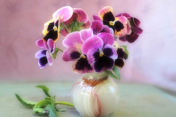 Florero con un ramo de violetas en la mesa