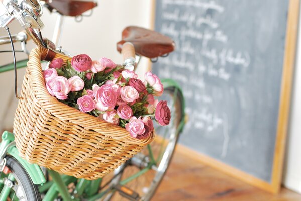 Vélo avec bouquet de fleurs roses dans un panier