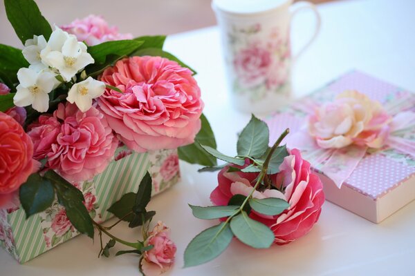 Коробка с подарком, кружка и розы на столе