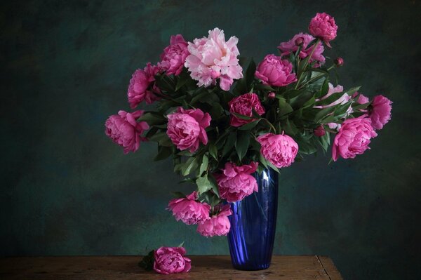Bukiet składający się z różowych piwonii stojących w niebieskim wazonie