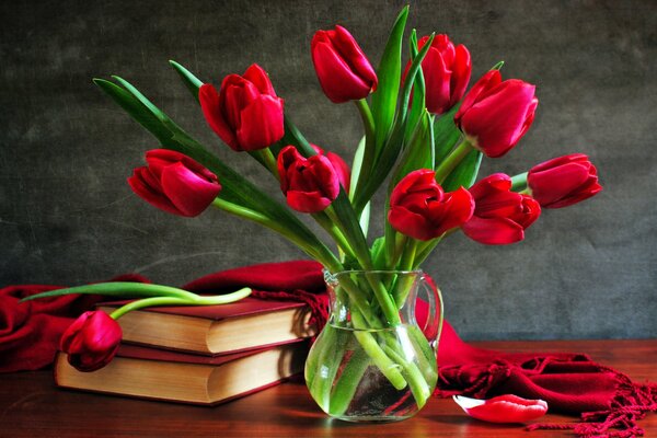 Red tulips in a vase on the table with books