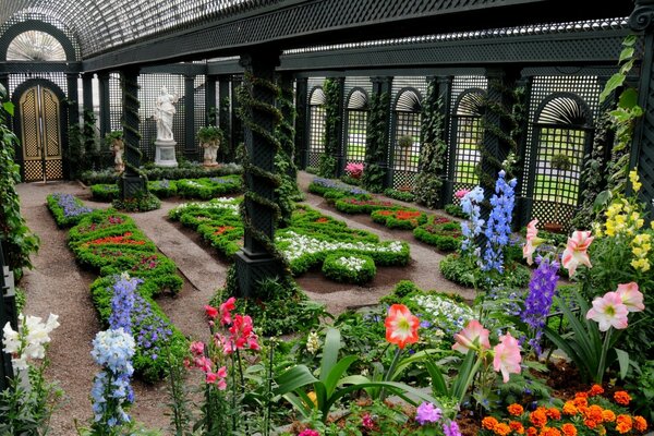 Schönes Gewächshaus mit Statuen und Blumenbeeten