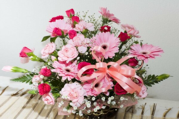 Pink flowers in a basket with a ribbon