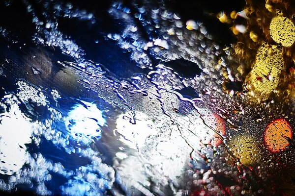 Night city lights on wet glass