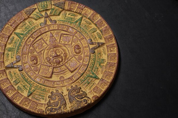 Calendrier aztèque ou symboles inhabituels sur un emblème rond sur fond noir