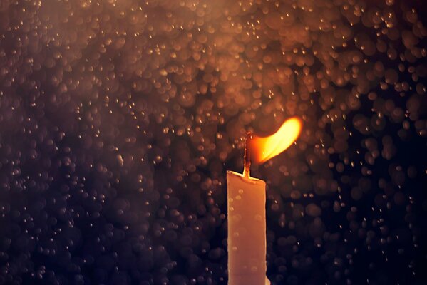 Vela encendida contra gotas de lluvia