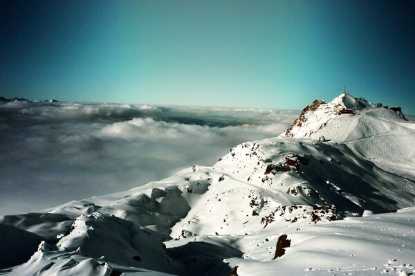 A snow-covered ridge of high mountains above the clouds